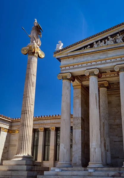 Columna con la estatua de Atenea, diosa griega antigua, patrón de la ciudad, por la entrada principal a la academia de Atenas, Grecia, en día del verano en cielo azul — Foto de Stock