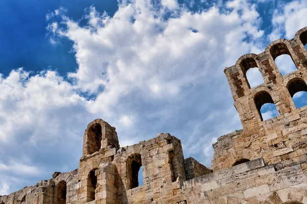 Acropolis Hill, Atina, Yunanistan 'daki Herodes Atticus Tiyatrosu' nun parlak mavi gökyüzü ve süper bulutlardaki görüntüsü. Klasik antik Yunan tiyatrosu kalıntıları