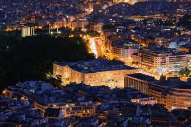 Syntagma Meydanı 'ndaki Yunan Parlamentosu gece görüşü ışıl ışıl parlıyor ve arkasında Olympian Zeus tapınağının kalıntıları Lycabettus tepesinden çekiliyor.,