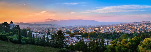 Atina, Yunanistan manzarası ve Pnyx Hill 'den gelen yerleşim alanları yumuşak akşam güneşinde, harika bir günbatımı gökyüzü. Atina Ulusal Gözlemevi önplanda.
