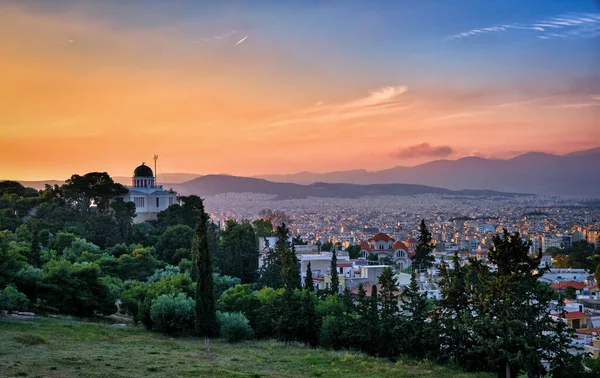 Blick auf Athen, Griechenland und Wohngebiete vom Pnyx-Hügel bei sanftem Sonnenlicht und herrlichem Sonnenuntergang. Nationales Observatorium von Athen im Vordergrund. — Stockfoto