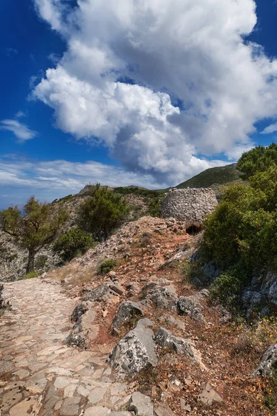 Paisaje griego o cretense, colinas con follaje primaveral, arbustos, olivos, camino rocoso, mitato. Cielo azul con nubes. Akrotiri, Chania, Creta, Grecia — Foto de Stock