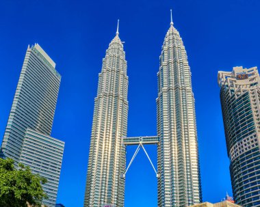 26 Kasım 2019 - Kuala Lumpur, Malezya: Petronas Kuleleri 'nin ikiz ikiz gökdelenleri, KLCC bölgesinin kentsel silueti, açık mavi gökyüzü, modern mimari, yemyeşil, yüksek binalar, Güneydoğu Asya' nın ünlü binaları, seyahat, turizm, iş merkezi