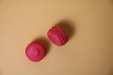 Sarı arka planda izole edilmiş iki pembe badem kurabiyesi. Resim kopyalama alanı içeriyor