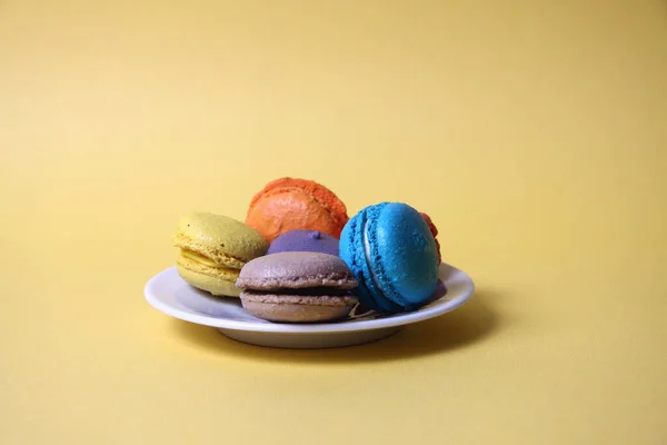 Macarons Van Verschillende Kleuren Een Schotel Geïsoleerd Gele Achtergrond Afbeelding — Stockfoto