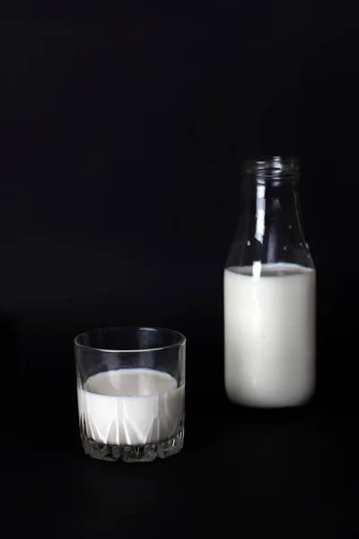 一个瓶子和一个在黑色背景上隔离的牛奶片 图像包含复制空间 垂直图像 — 图库照片