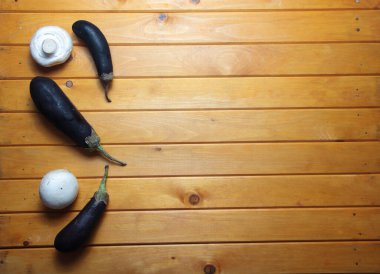 Tahta arka planda patlıcanlar ve şampiyonlar yatıyordu. Resim kopyalama alanı içeriyor