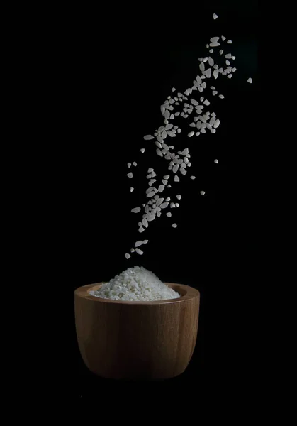 Pirinç Siyah Arka Planda Ahşap Kaseye Dökülüyor Uçan Yiyecek Kavramı — Stok fotoğraf