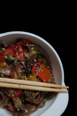 Bir kase rafadan erişte ve yemek çubuğu siyah arka planda izole edilmiş. Resim kopyalama alanı içeriyor