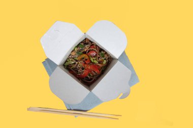 wok box ve yemek çubukları sarı arkaplanda izole edilmiş düz resim kopyalama alanı içerir