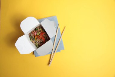 wok box ve yemek çubukları sarı arkaplanda izole edilmiş düz resim kopyalama alanı içerir
