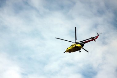 Mavi bulutlu gökyüzünde uçan bir helikopter. Resim kopyalama alanı içeriyor. Yatay resim