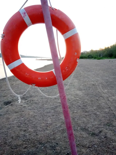 orange life saver on the beach near the river. Evening landscape. Security concept