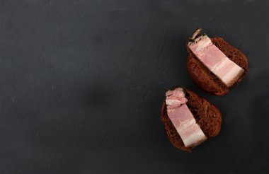 Siyah arka planda izole edilmiş siyah ekmek çörekleri üzerinde domuz pastırması. Resim kopyalama alanı içeriyor