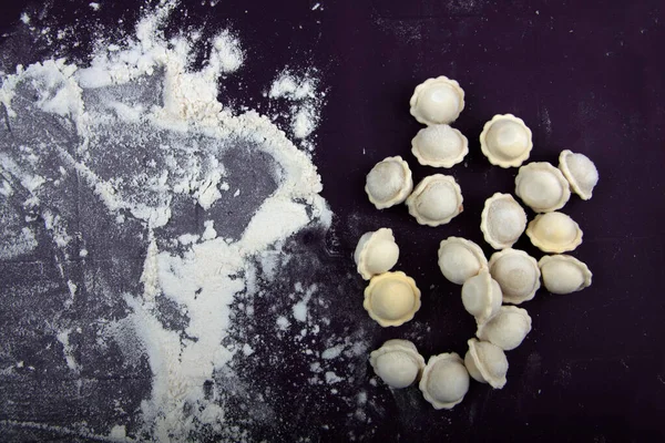 Pişmemiş Rus pelmeni ve un hasırlı düz yerde yatıyordu. Etli hamur tatlısı yapma süreci. Resim kopyalama alanı içeriyor