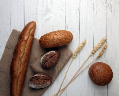 Taze ekmek - çörekler, baget ve ahşap zemin üzerinde bez peçete üzerine buğday kulakları. Resim kopyalama alanı içeriyor