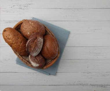 Hasır sepetteki taze ekmek ahşap masanın üzerinde, mavi peçete üzerinde düz duruyordu. Resim kopyalama alanı içeriyor