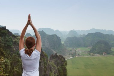 Genç kadın tutmak sakin ve güzel manzaralı tepenin üst kısmında yoga uygulamak ise derin derin düşünür