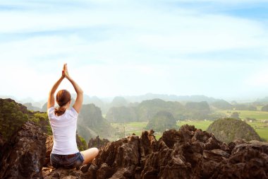 Genç kadın tutmak sakin ve güzel manzaralı tepenin üst kısmında yoga uygulamak ise derin derin düşünür