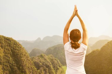 Genç kadın tutmak sakin ve güzel manzaralı tepenin üst kısmında yoga uygulamak ise derin derin düşünür