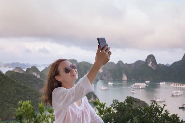 Be online in travel. Modern technology and communication. young woman doing selfie on the top of hill with sea and islands background