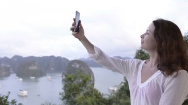Seyahat çevrimiçi olması. Modern teknoloji ve iletişim. Genç kadının selfie üst kısmında hill ile deniz ve adalar arka plan yapması
