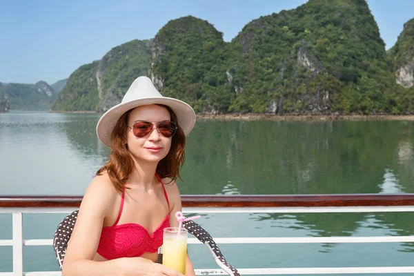 young woman on boat sitting on table and drinking the juice among the islands