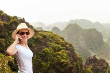 Modern teknoloji ve iletişim. Seyahat çevrimiçi olması. yürüyüş ve kavram trekking. Dağ tepe üzerinde akıllı telefon kullanan genç kadın