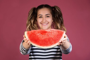 Komik portre mutlu gülümseyen genç kız pembe renkli arka plan üzerinde dilim karpuz holding