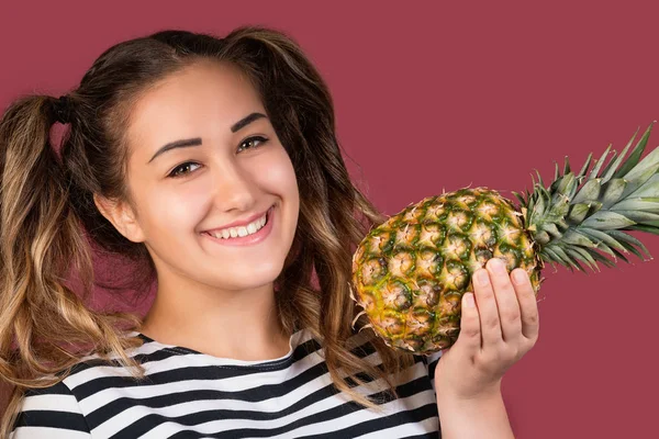 Portrait of cool girl with pineapple over pink background. Healthy food concept