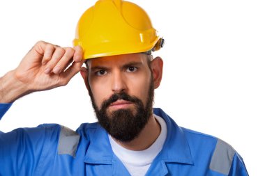 Sert şapkalı inşaatçı, foreman ya da tamirci miğferine dokunuyor. Sakallı, sakallı, şapkalı adam işçi. Portre mimarı mimar, inşaat mühendisi çalışıyor. Izole