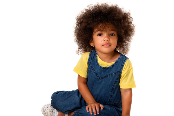 Portrait of african-american lovely little  girl sitting and  looking to camera, isolated