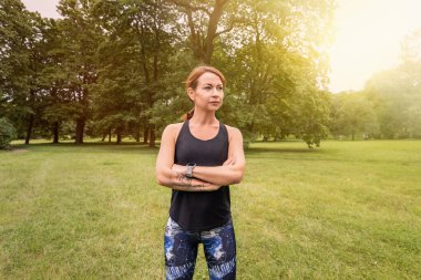 Güzel ve atletik bir kız. Koşmak için kıyafetleri var. Elleri göğsünde duruyor.