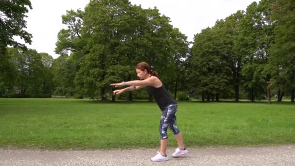 ジョギング前に緑の公園で運動するスローモーション若いスポーツ女性 — ストック動画