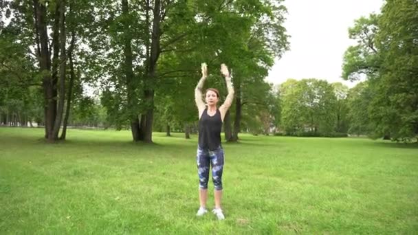 ジョギング前に緑の公園で運動するフィット感とスポーティ女性 — ストック動画