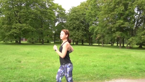 緑の公園を走るスローモーションの若いスポーツ女性 — ストック動画