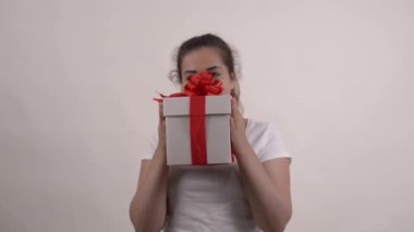 Beyaz tişörtlü beyaz kız hediye kutusunu tutuyor.