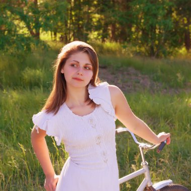 bir bisiklet parlak güneşli bir günde forest yakınındaki ile yürüyen kadın