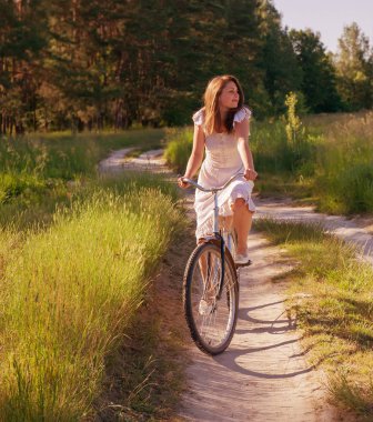 Kız bir bisiklet ile yaz günü kırsal kesimde gidiyor