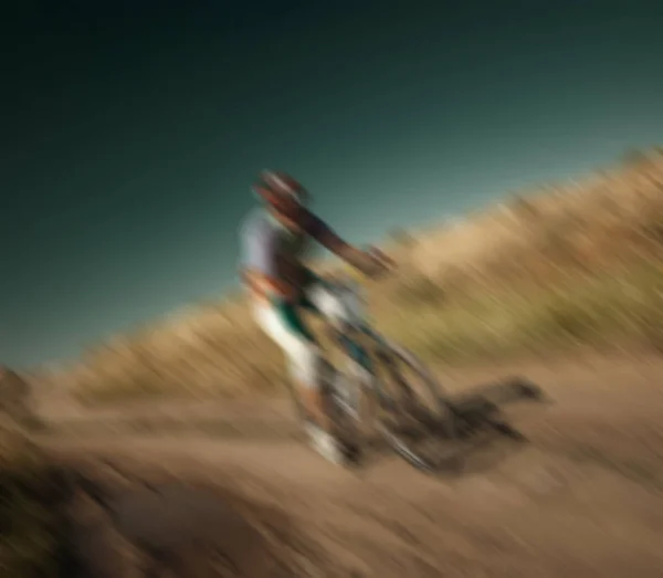 blurred background, racing cyclist rides on rough terrain