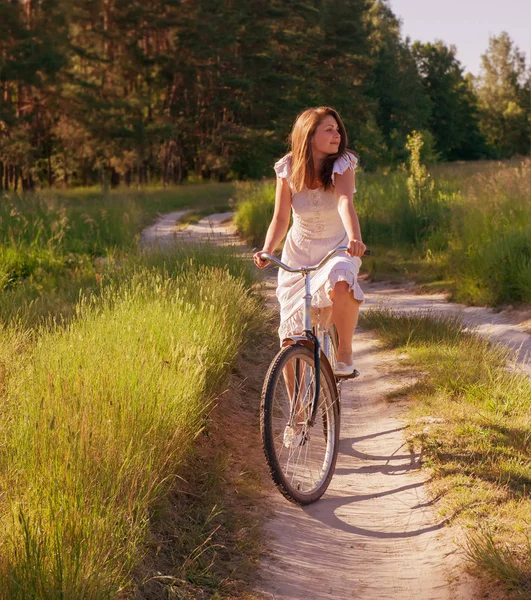 Kız bir bisiklet ile yaz günü kırsal kesimde gidiyor