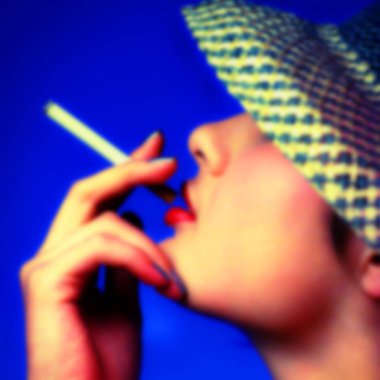 arka plan bulanık, bir kadın bir sigara el ve dudakları şapkasını tutar