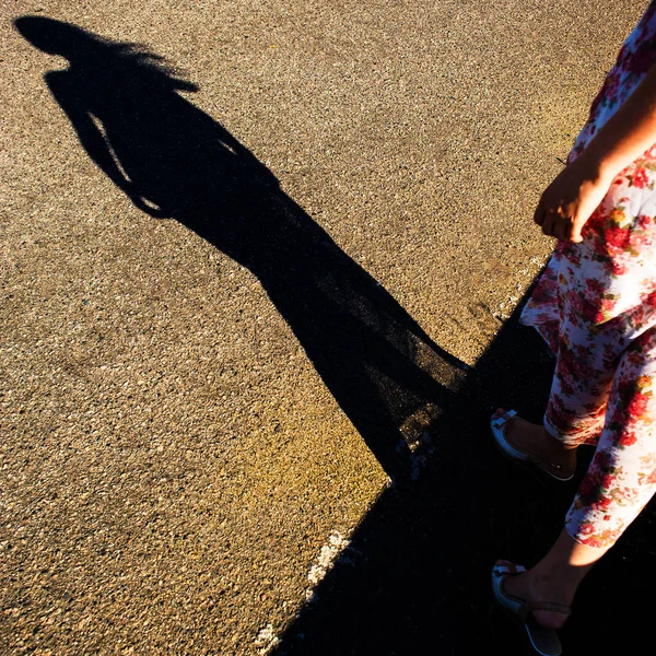 Shadow of a female figure on the asphalt road