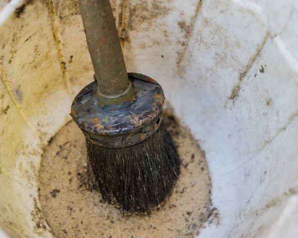 old brush to paint in a container with sand