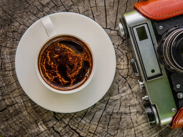 木桌上的一杯咖啡和一台旧的胶卷相机 — 图库照片