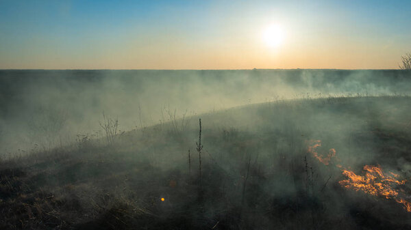 smoke and fire, burning dry grass on the hillside. Villager they set fire to dry grass so that young grass would grow to feed animals. Early spring in the countryside.