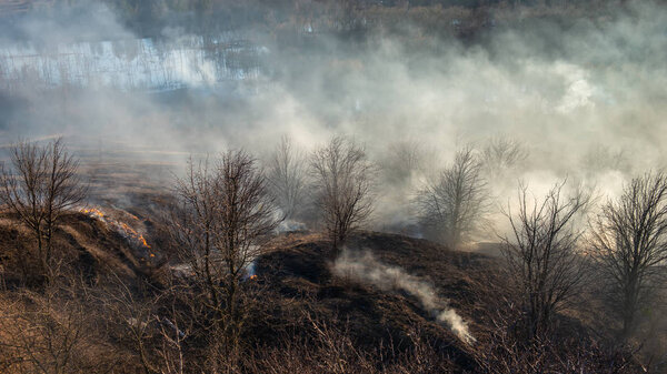 smoke and fire, burning dry grass on the hillside. Villager they set fire to dry grass so that young grass would grow to feed animals. Early spring in the countryside.