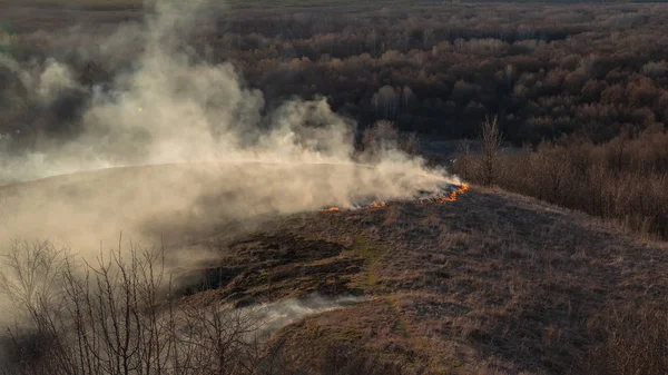 smoke and fire, burning dry grass on the hillside. Villager they set fire to dry grass so that young grass would grow to feed animals. Early spring in the countryside.