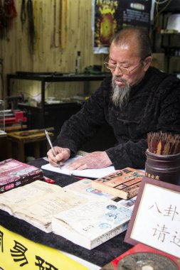 Zhujiajiao, Çin - 4 Nisan 2016: Zhujiajiao, Çin'deki beyaz kağıt parçası üzerinde hiyeroglif yazılı Çinli adam