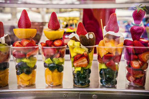 Смешанные срезанные свежие летние порции фруктов на рынке. Фрукты на прилавке фруктового рынка, Италия
